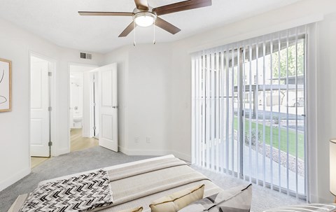 A bedroom with a bed and a ceiling fan.