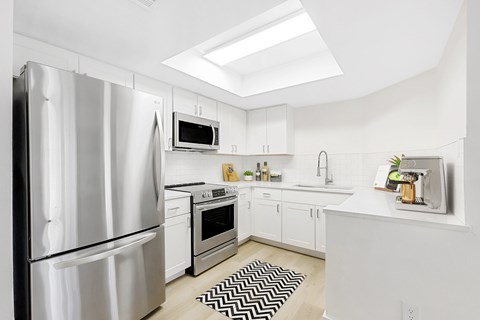 A modern kitchen with a stainless steel refrigerator and white cabinets.
