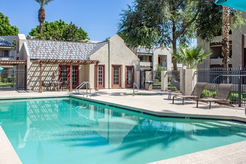A swimming pool in front of a building with a red door.