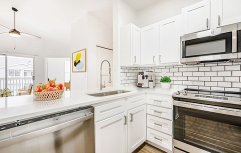 A kitchen with white cabinets and a black and white tiled backsplash.