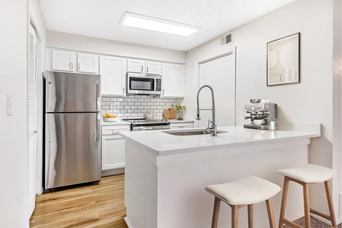 A kitchen with a white counter and a stainless steel refrigerator.