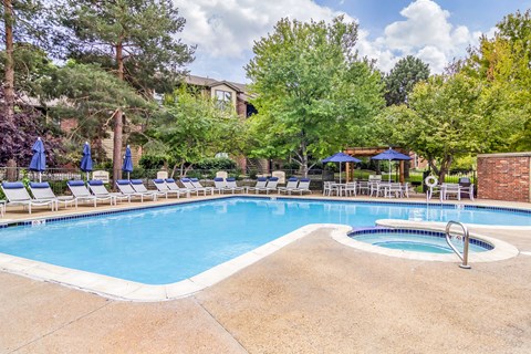 A pool surrounded by trees and chairs.