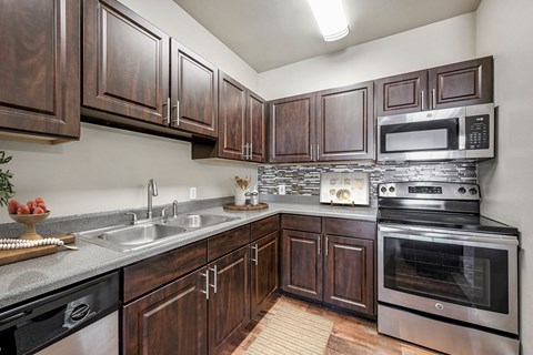 A kitchen with dark wood cabinets and stainless steel appliances.