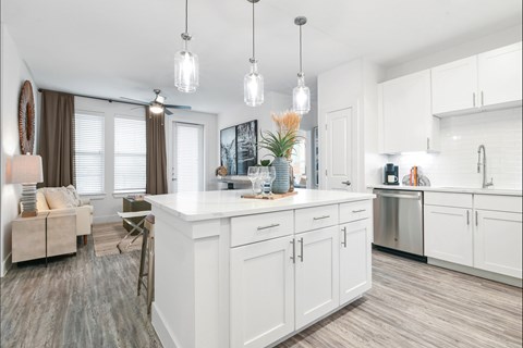 A kitchen with white cabinets and a wooden floor.