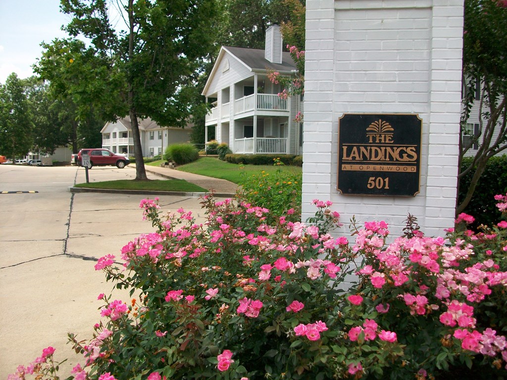 a sign for the landing on the side of a building with pink flowers