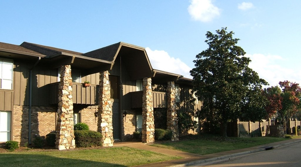 a building with stone pillars and a tree in front of it