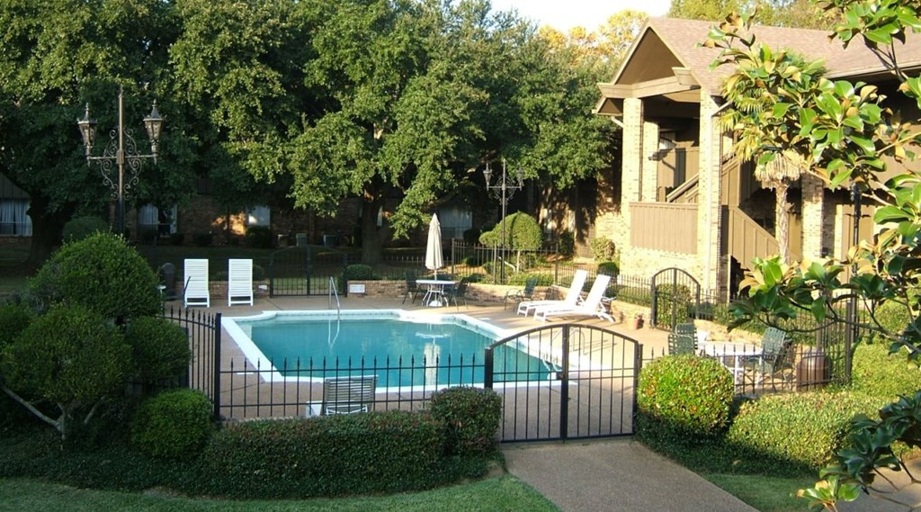 a pool in front of a house with a black fence