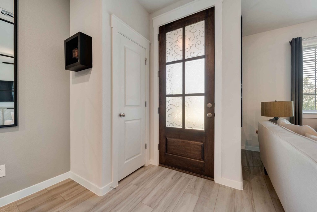a door with a glass window in a room with white walls and wood floors