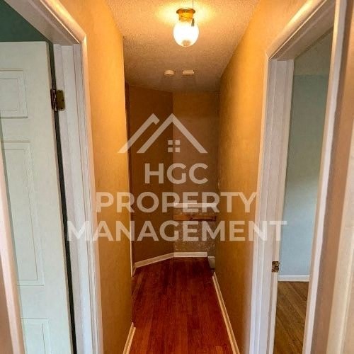 a hallway with a door to a room with a hard wood floor