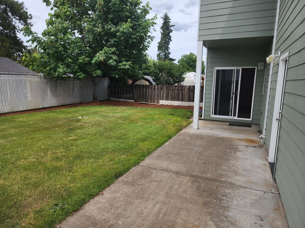 a yard with a sidewalk and a house with a fence