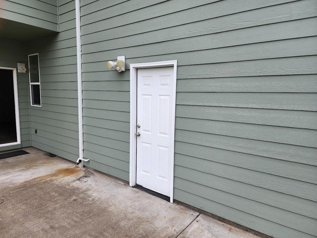 a white door on the side of a green house