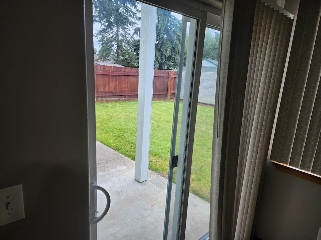 a view of the backyard from the inside of a house with sliding glass doors