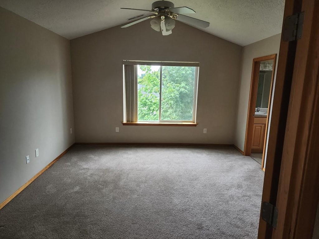 a empty room with a ceiling fan and a window