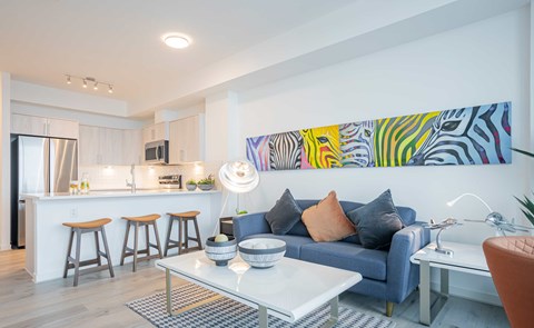 A modern living room with a blue couch and a colorful abstract painting on the wall.