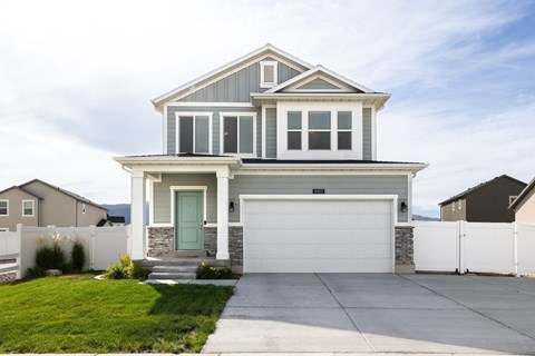 a white house with a garage door and a lawn