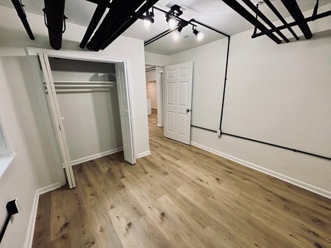 A room with a white door and a white wall with a wooden floor.