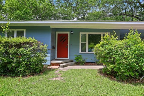 the front of a blue house with a red door