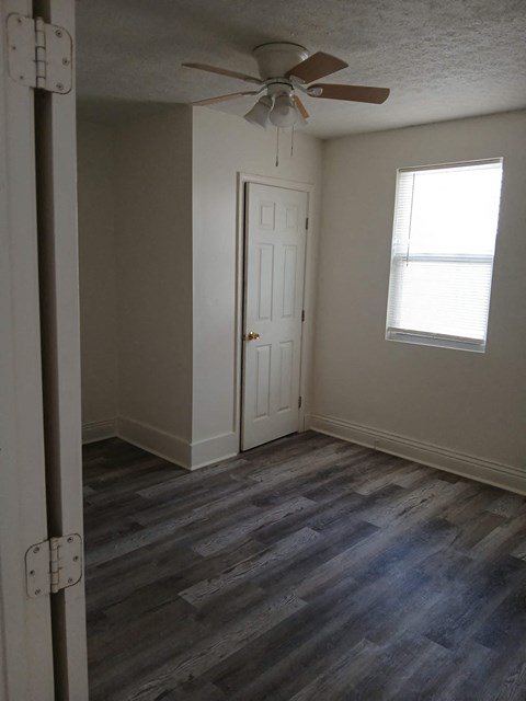 an empty room with a ceiling fan and a window