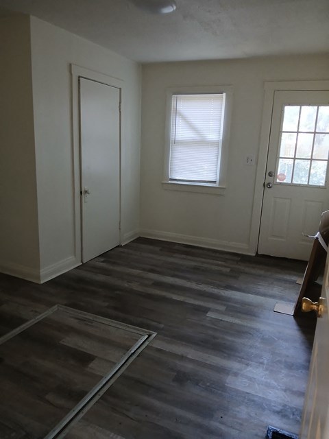 an empty room with wooden floors and a door and a window