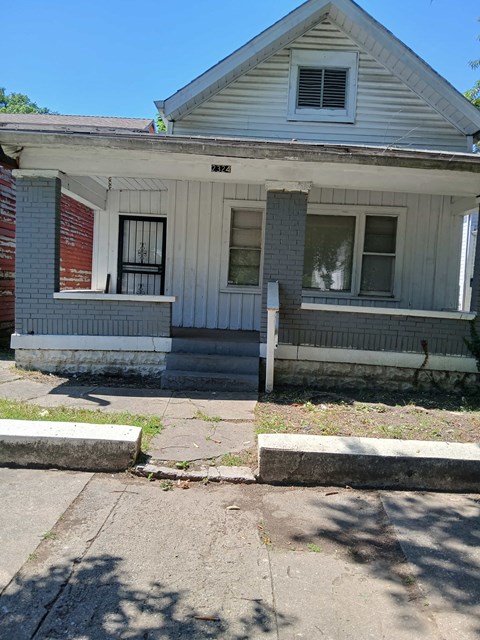 the front of a small white house with a porch