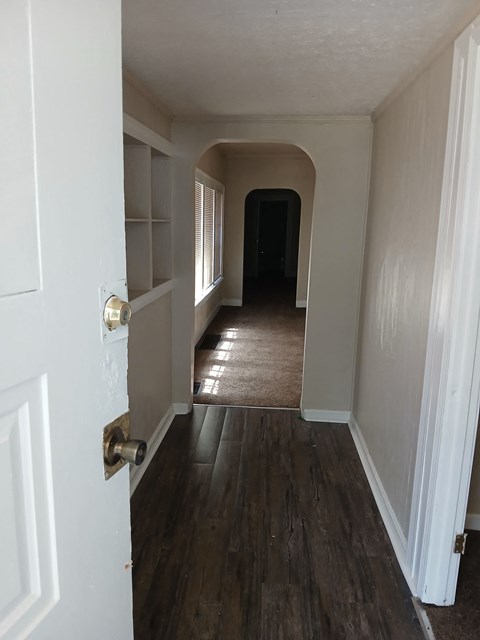 a look down the hallway of a house with wood flooring and white walls