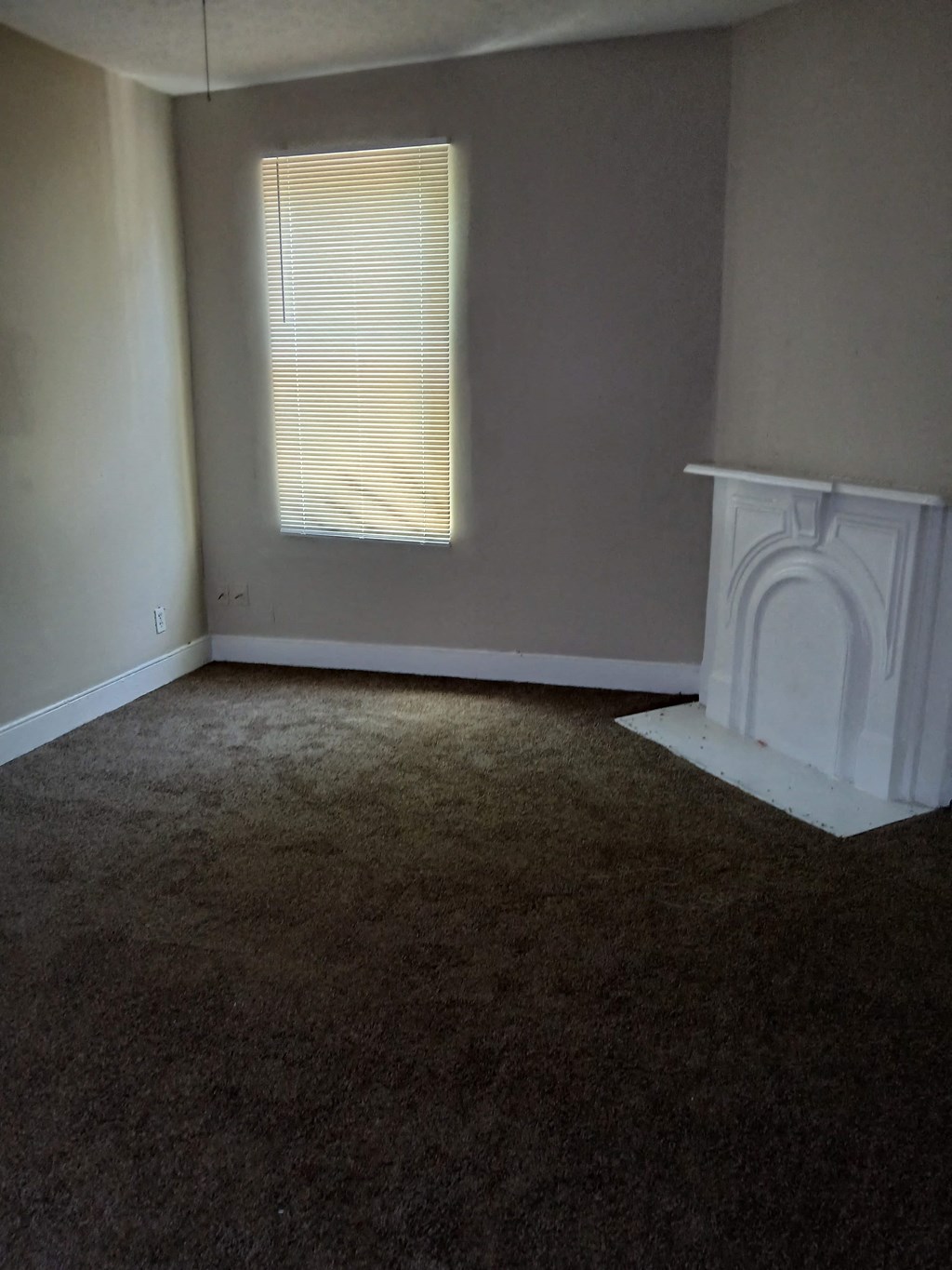 an empty room with a fireplace and a window