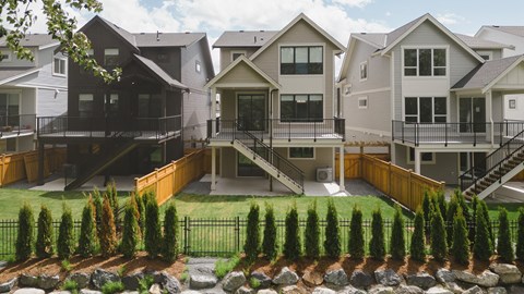 an exterior view of a group of houses with a lawn and a garden