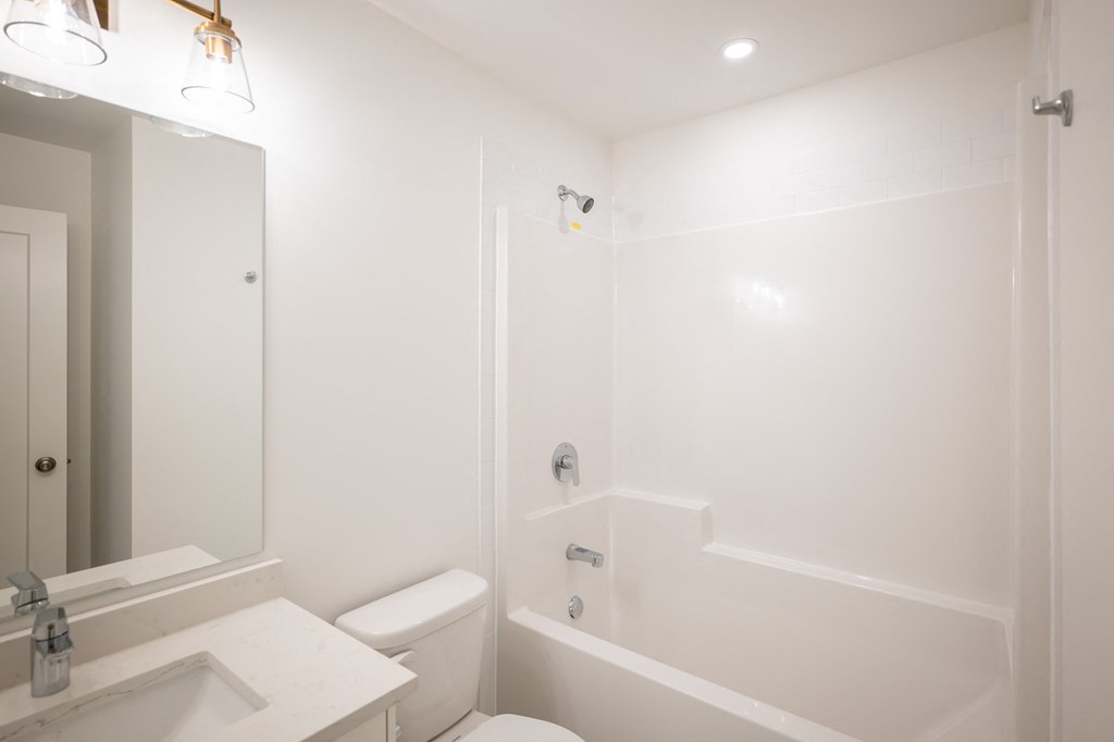 a white bathroom with a tub and a toilet and a sink