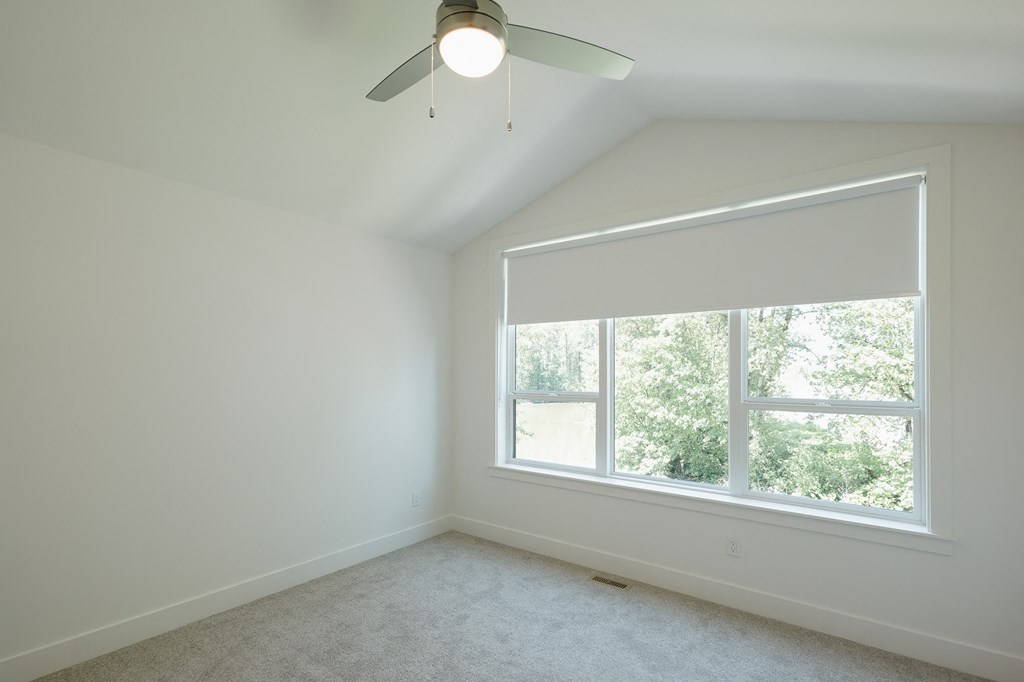 an empty bedroom with a large window and a ceiling fan