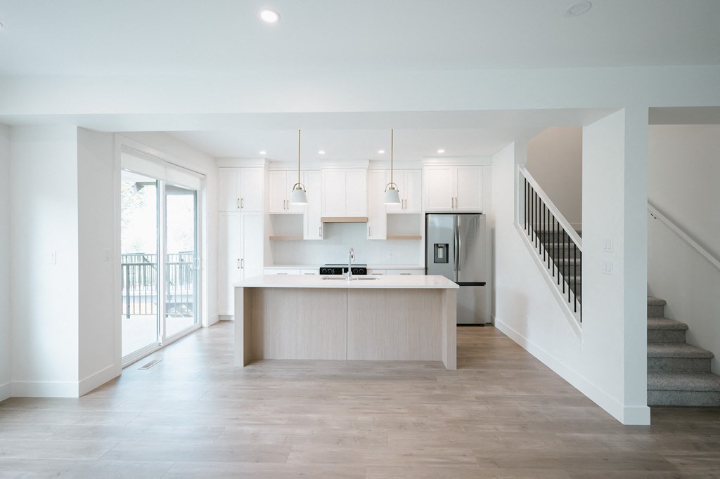 a kitchen with white cabinets and a white counter top and a staircase