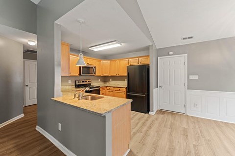 A kitchen with a black refrigerator and wooden cabinets.