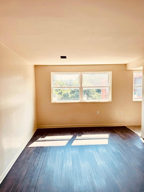 A room with a window and a wooden floor.