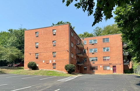 A red brick building with a parking lot in front.
