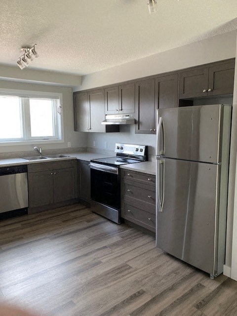 a kitchen with stainless steel appliances and wooden floors