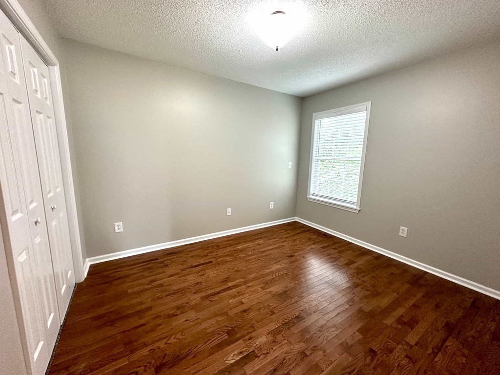 a empty living room with wood floors and a window