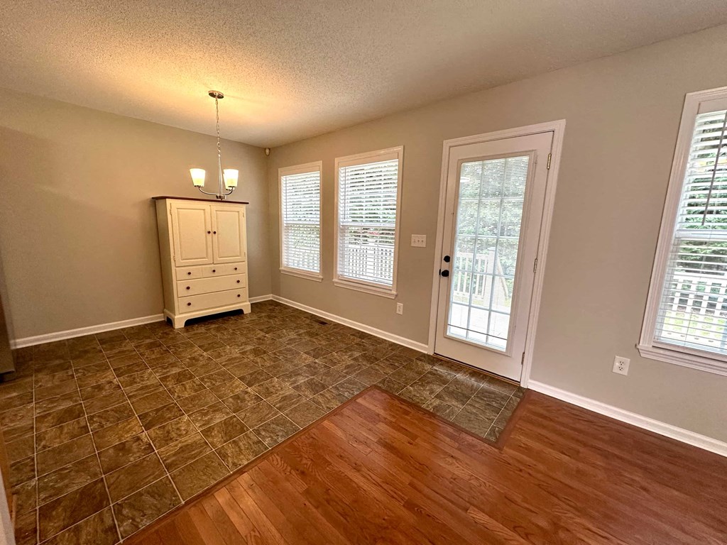 an empty living room with wood floors and a door to a patio