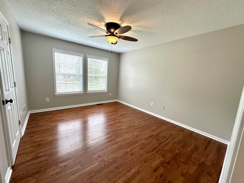 an empty living room with a ceiling fan and wood floors