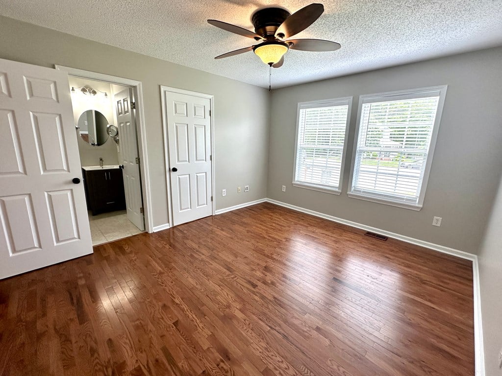 an empty living room with wood floors and a ceiling fan