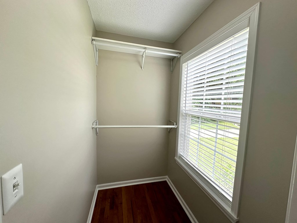 a small closet with a large window and a wooden floor