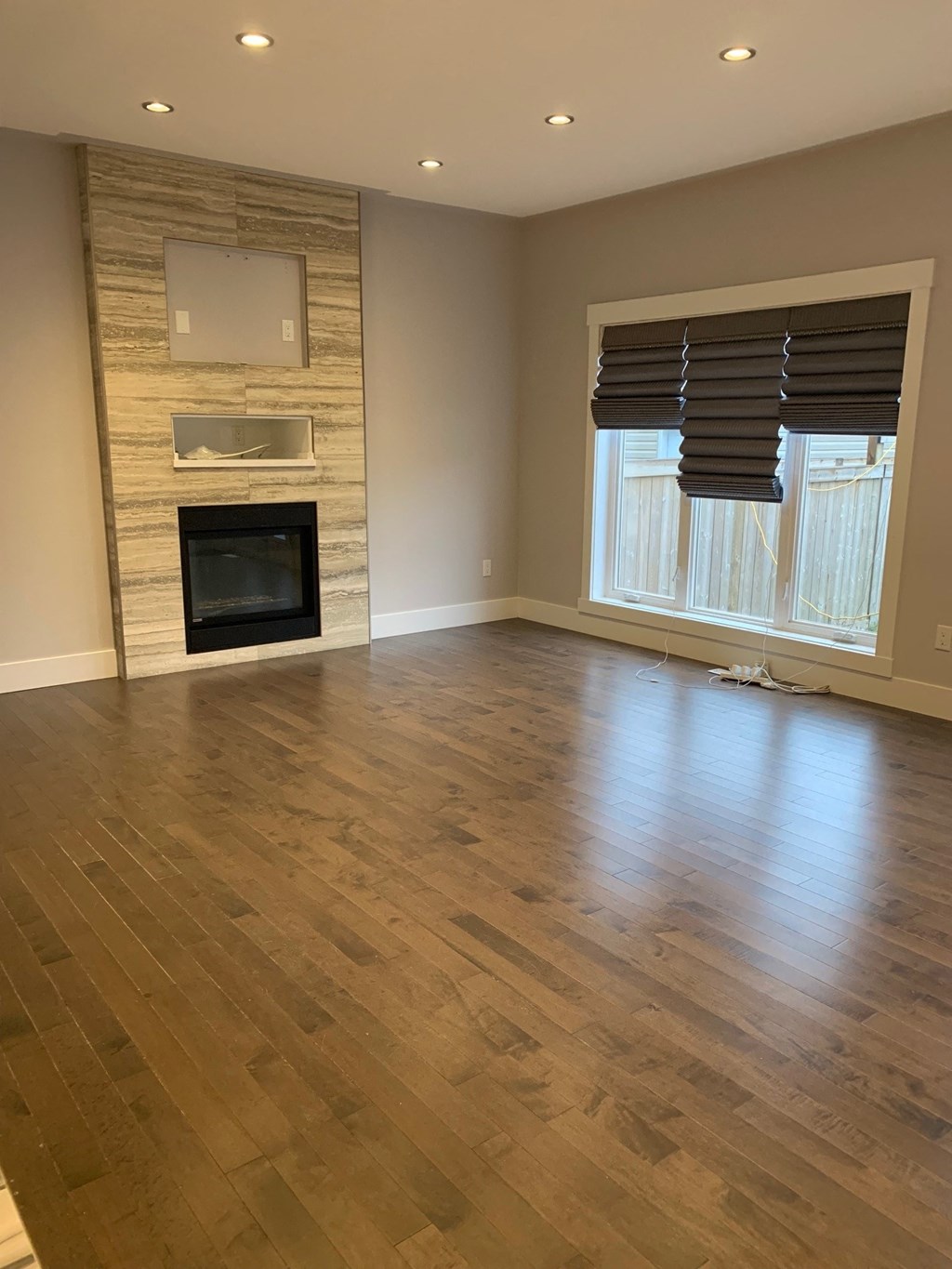 an empty living room with a fireplace and wooden floors