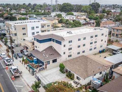 A large white building with a blue stripe on the side is surrounded by other buildings and vehicles.
