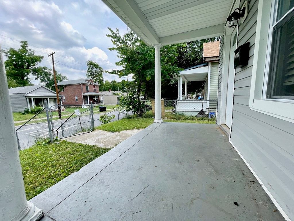 the front porch of a white house with a concrete driveway