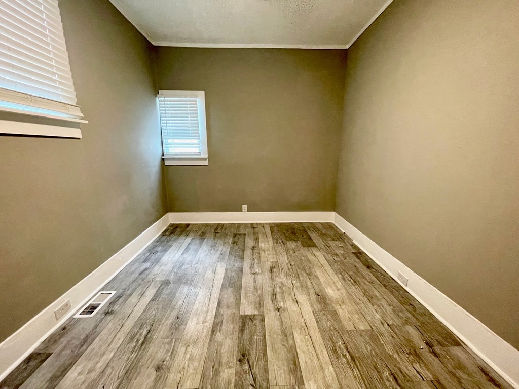 an empty room with wood floors and a window