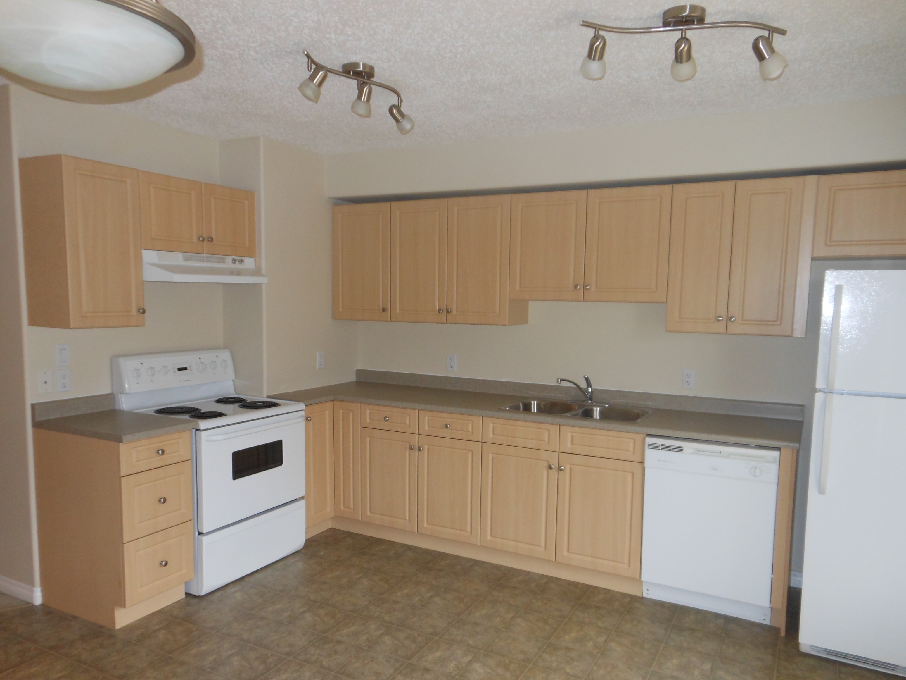 an empty kitchen with white appliances and wooden cabinets