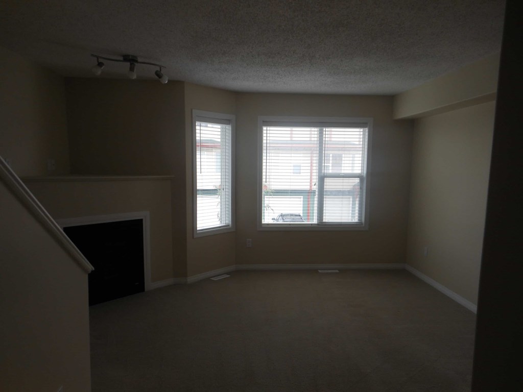 an empty living room with two windows and a fireplace
