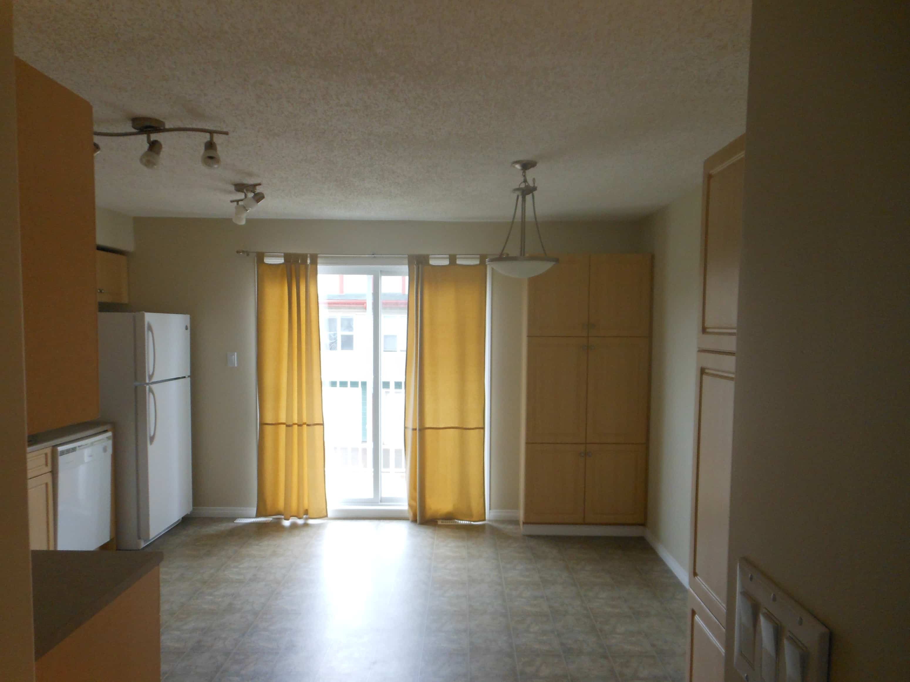 an empty kitchen with the doors open to the living room