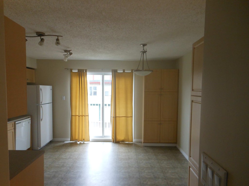 an empty kitchen with the doors open to the living room