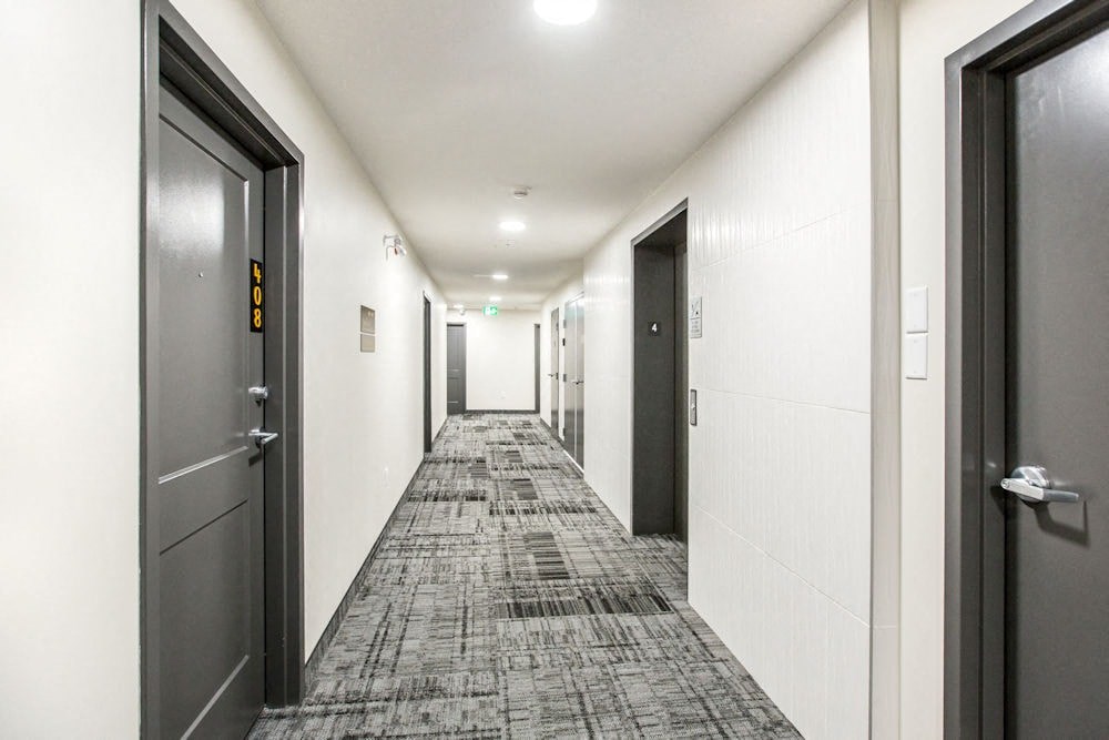 a long hallway with doors and white walls and tiled floors