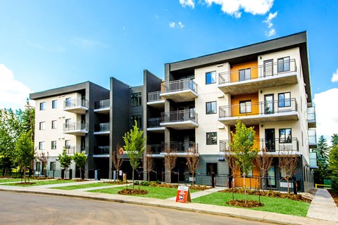 a row of apartment buildings with grass and trees