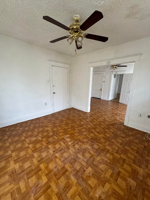 an empty living room with wood flooring and a ceiling fan